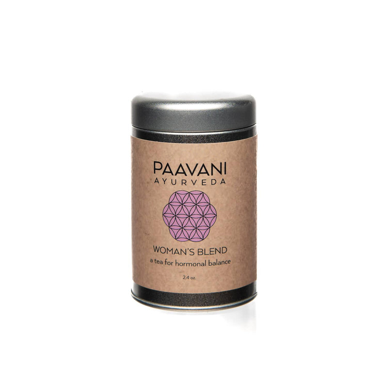 Eine zylindrische Metalldose mit silbernem Deckel und einem hellbraunen Etikett. Das Etikett trägt die Aufschrift "PAAVANI AYURVEDA" mit einem rosa geometrischen Muster und "WOMAN'S BLEND a tea for hormonal balance 2.4 oz.".