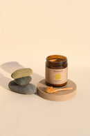 Glas mit Paavani Ayurveda Golden Milk (Kurkumapulver) und einem kleinen Löffel Pulver, präsentiert mit gestapelten Steinen.