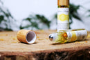 Eine Rollerflasche mit gelbem ätherischem Öl liegt neben ihrer Bambuskappe auf einer Holzoberfläche.