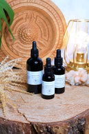 Drei schwarze Tropfflaschen mit Lion's Mane Flüssigextrakt stehen auf einer Holzscheibe mit einer goldenen Lampe und Kristallen.