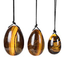 Drei polierte eiförmige Tigerauge-Steine hängen an schwarzen Schnüren.