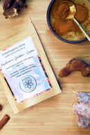 Eine Draufsicht auf eine „Mushroom Golden Latte“ adaptogene Mischungsverpackung neben einer Schale mit Pulver und Gewürzen.