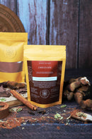 Zwei Päckchen der Choco Chai Mischung mit Zimt, Kakao und Gewürzen dargestellt.