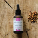 Braunes Glasläschchen mit Pipette und Beschrieb des Produkts auf holzigem Hintergrund.