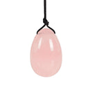 Ein glatter, polierter Yoni-Ei oder Anhänger aus hellrosa Rosenquarz, der an einer verknoteten schwarzen Schnur hängt.
